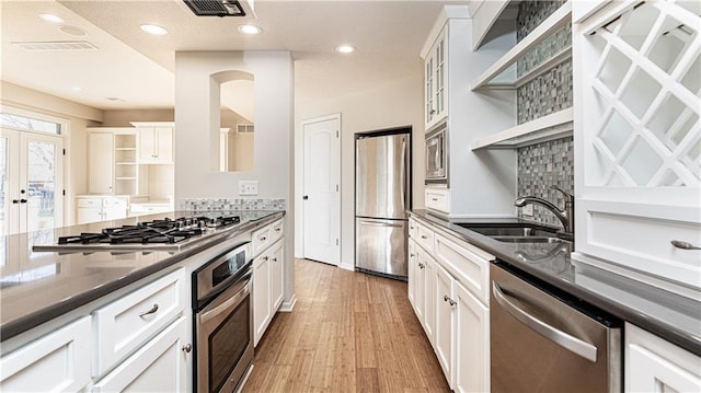 kitchen with open shelves, visible vents, dark countertops, a sink, and stainless steel appliances