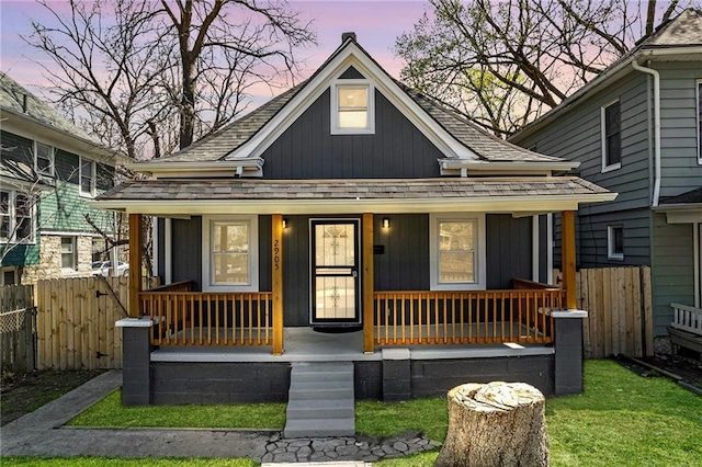 2905 Wabash Ave, Kansas City, MO 64109 - view of front facade featuring a porch, board and batten siding, fence, and a shingled roof