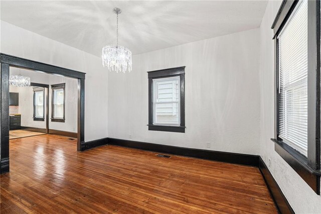 2905 Wabash Ave, Kansas City, MO 64109 - spare room featuring baseboards, wood-type flooring, a notable chandelier, and visible vents