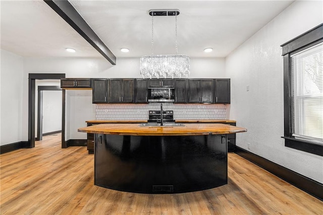 2905 Wabash Ave, Kansas City, MO 64109 - kitchen with stainless steel microwave, butcher block countertops, an inviting chandelier, light wood-style floors, and a sink