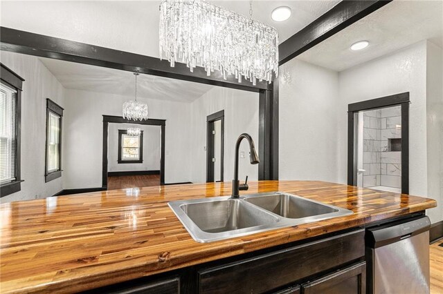 2905 Wabash Ave, Kansas City, MO 64109 - kitchen featuring light wood-style flooring, an inviting chandelier, a sink, butcher block countertops, and stainless steel dishwasher