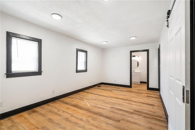 2905 Wabash Ave, Kansas City, MO 64109 - unfurnished bedroom featuring light wood-type flooring, ensuite bathroom, and baseboards