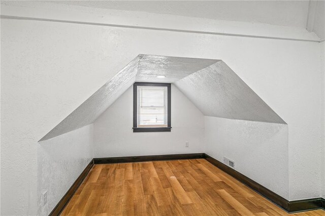2905 Wabash Ave, Kansas City, MO 64109 - bonus room featuring vaulted ceiling, visible vents, wood finished floors, a textured wall, and baseboards