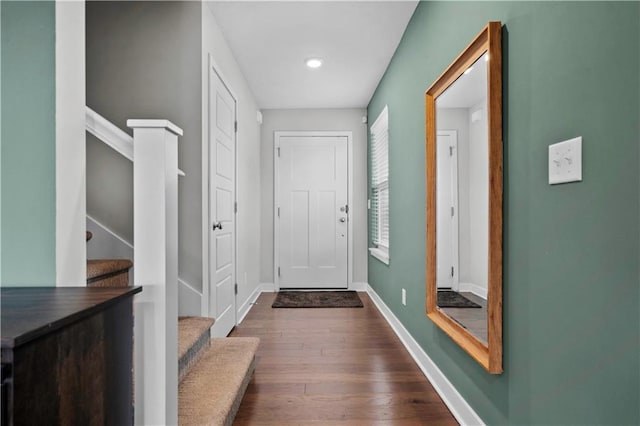 doorway featuring baseboards, stairway, and dark wood finished floors