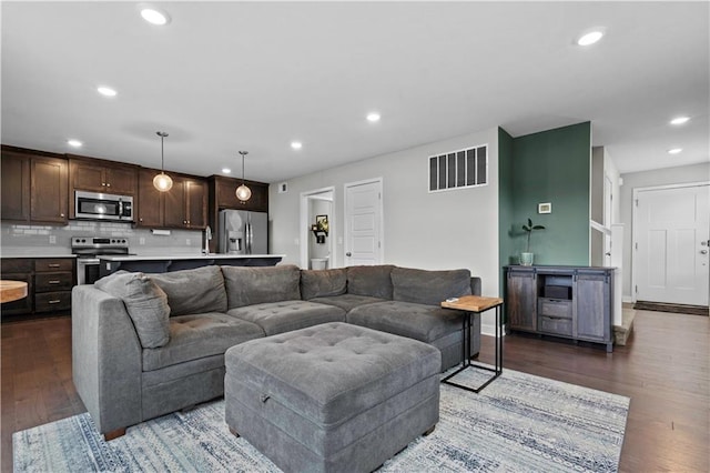 living room featuring wood finished floors, recessed lighting, baseboards, and visible vents