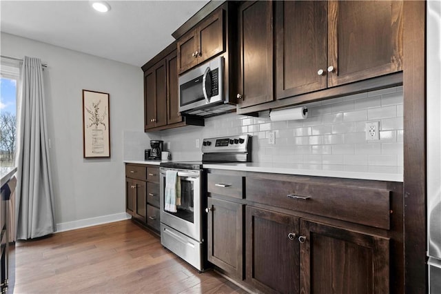 kitchen with decorative backsplash, light countertops, light wood-style flooring, stainless steel appliances, and dark brown cabinetry