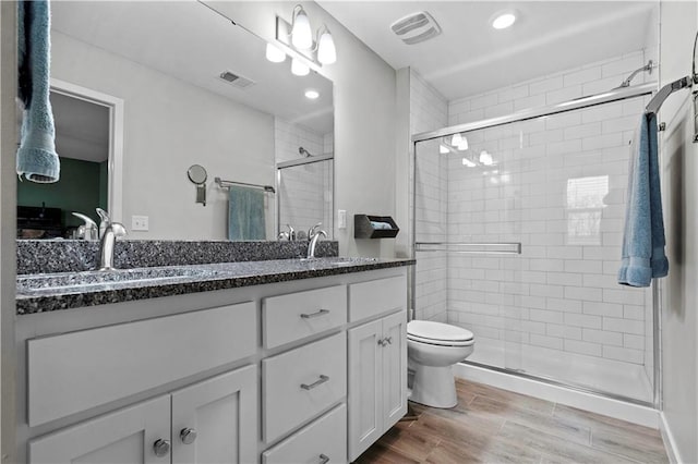 bathroom featuring visible vents, a sink, toilet, and a shower stall