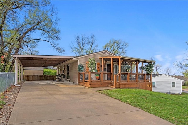 view of front of property with driveway, fence, a front yard, and an attached carport