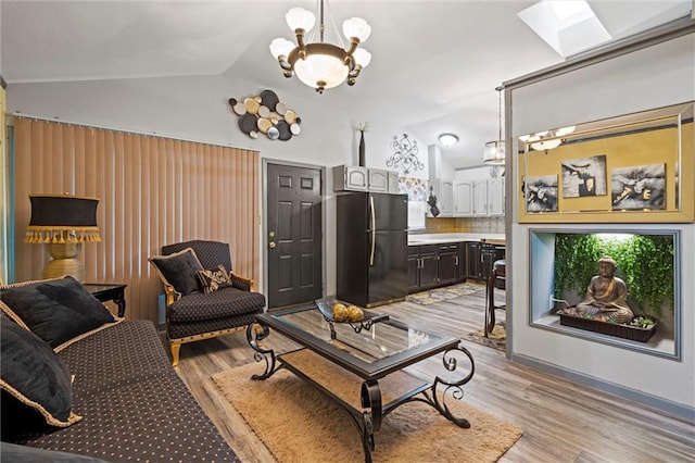 living area featuring lofted ceiling, light wood-style flooring, and an inviting chandelier