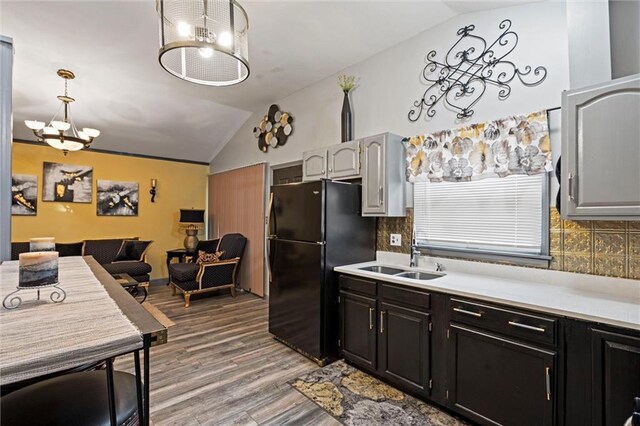 kitchen with vaulted ceiling, freestanding refrigerator, a sink, and an inviting chandelier