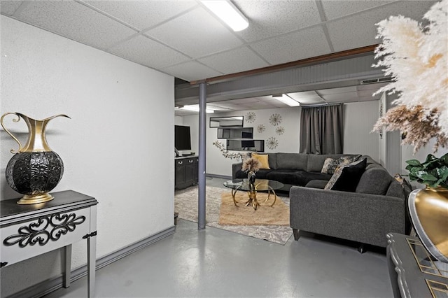 living room with finished concrete flooring, a wall mounted AC, and a paneled ceiling