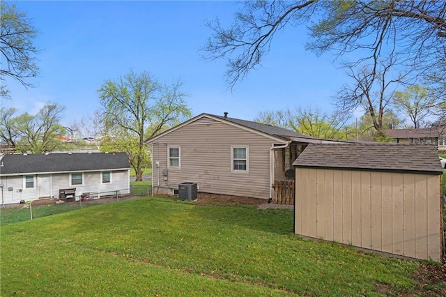 back of house with an outbuilding, fence, a storage shed, central AC, and a lawn