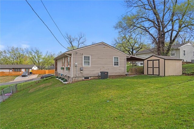 rear view of property with fence, central AC, a lawn, an outbuilding, and a shed