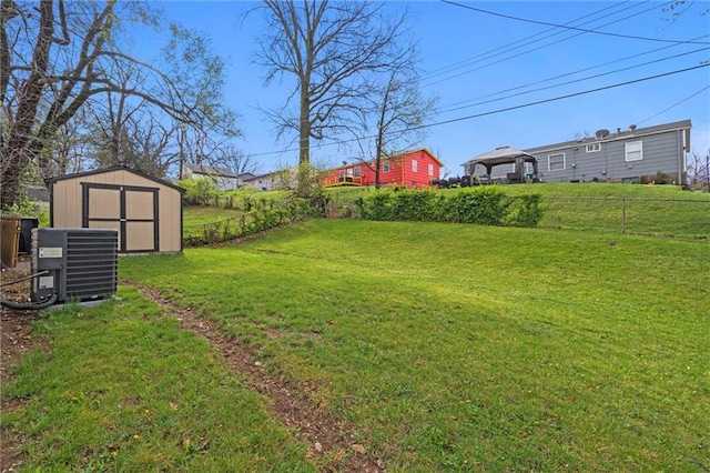 view of yard with central AC unit, a shed, an outbuilding, and a fenced backyard