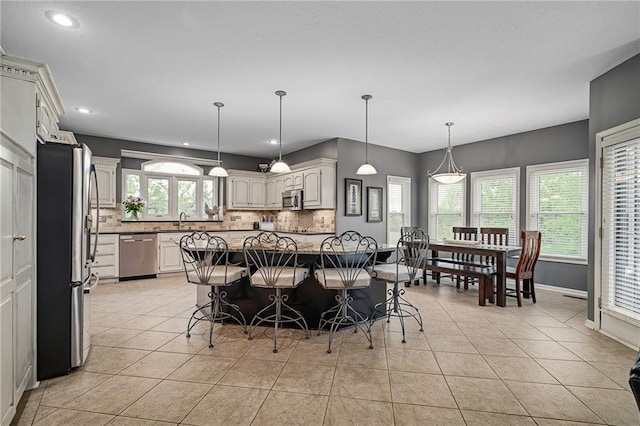 kitchen with stainless steel appliances, backsplash, a sink, light tile patterned flooring, and a breakfast bar