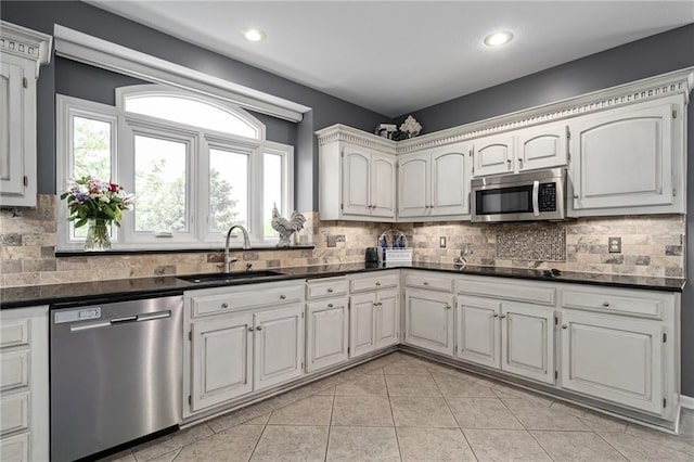 kitchen with stainless steel appliances, a sink, dark countertops, decorative backsplash, and recessed lighting