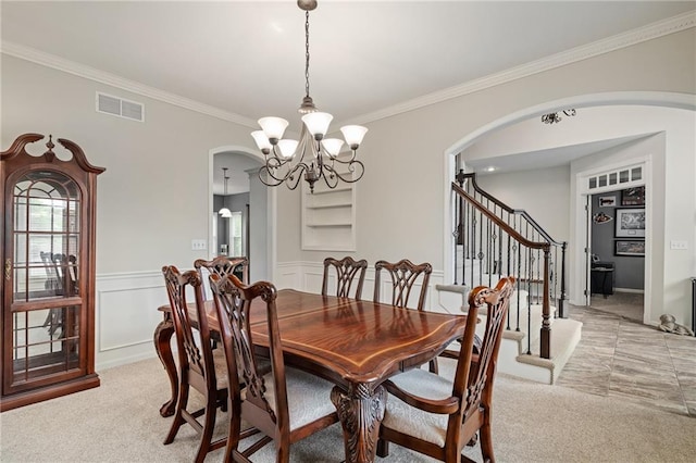 dining area with arched walkways, light carpet, crown molding, a chandelier, and stairs