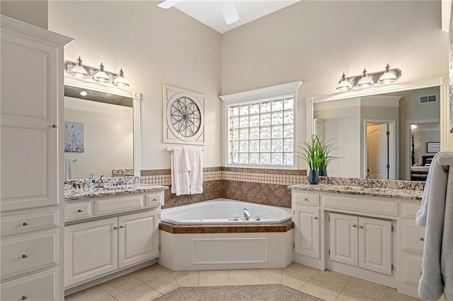 bathroom with tile patterned floors, two vanities, a garden tub, and ceiling fan
