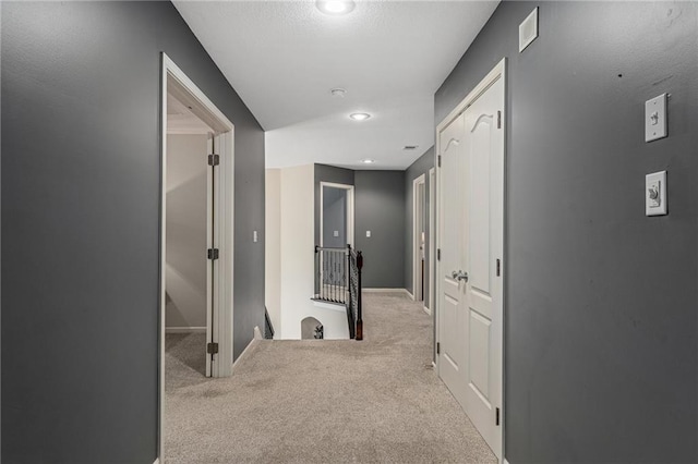 hall featuring an upstairs landing, carpet, baseboards, and recessed lighting