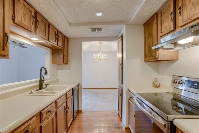 kitchen featuring visible vents, a sink, under cabinet range hood, brown cabinets, and stainless steel appliances