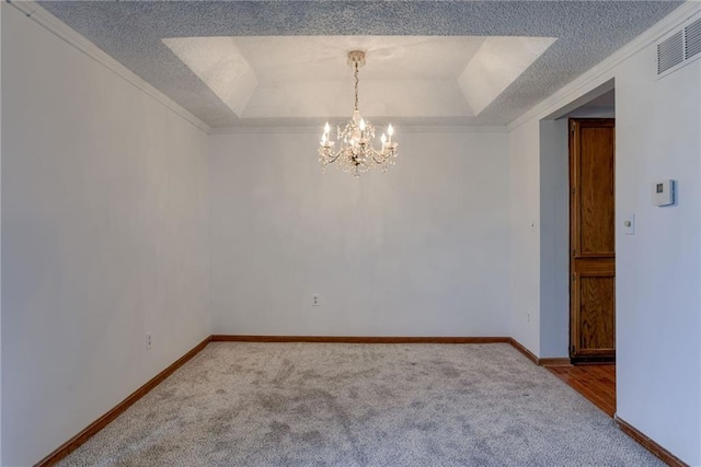 carpeted empty room featuring visible vents, a raised ceiling, a notable chandelier, ornamental molding, and a textured ceiling