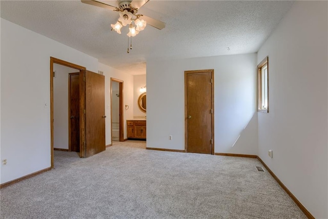 unfurnished bedroom with light carpet, a textured ceiling, and baseboards
