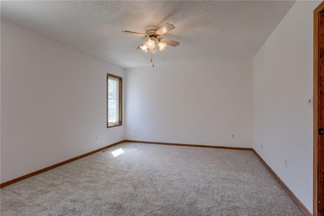 spare room with a textured ceiling, ceiling fan, baseboards, and carpet flooring