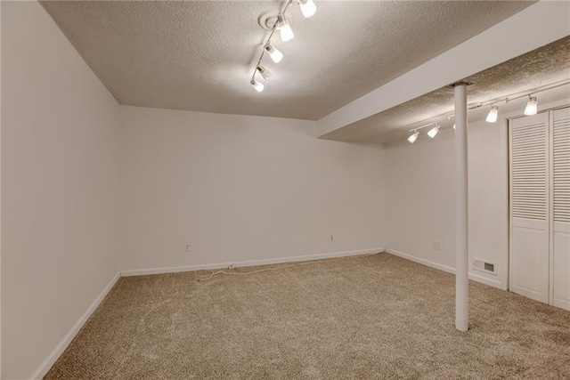 finished below grade area with visible vents, carpet flooring, and a textured ceiling