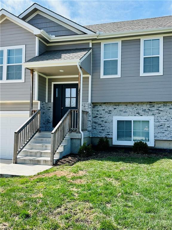 view of front facade with a porch, brick siding, an attached garage, and a front lawn