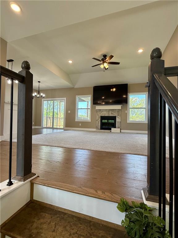 unfurnished living room with plenty of natural light, baseboards, and a glass covered fireplace