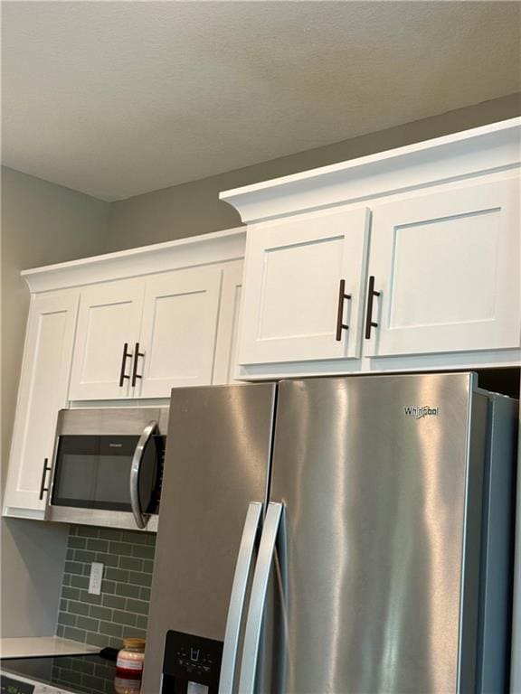 room details with stainless steel appliances, white cabinetry, and backsplash