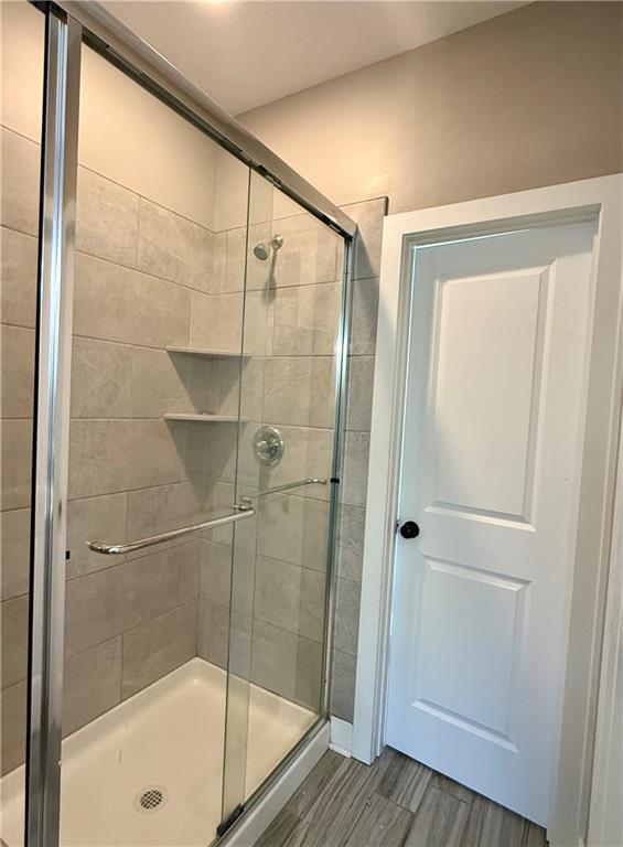 bathroom with wood finished floors and a shower stall