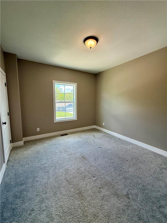 empty room featuring carpet, visible vents, and baseboards