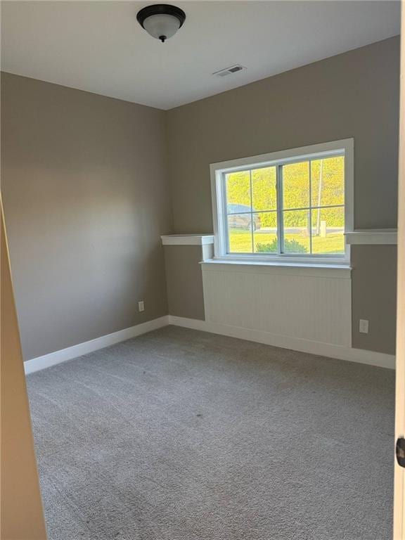 carpeted spare room featuring visible vents and baseboards