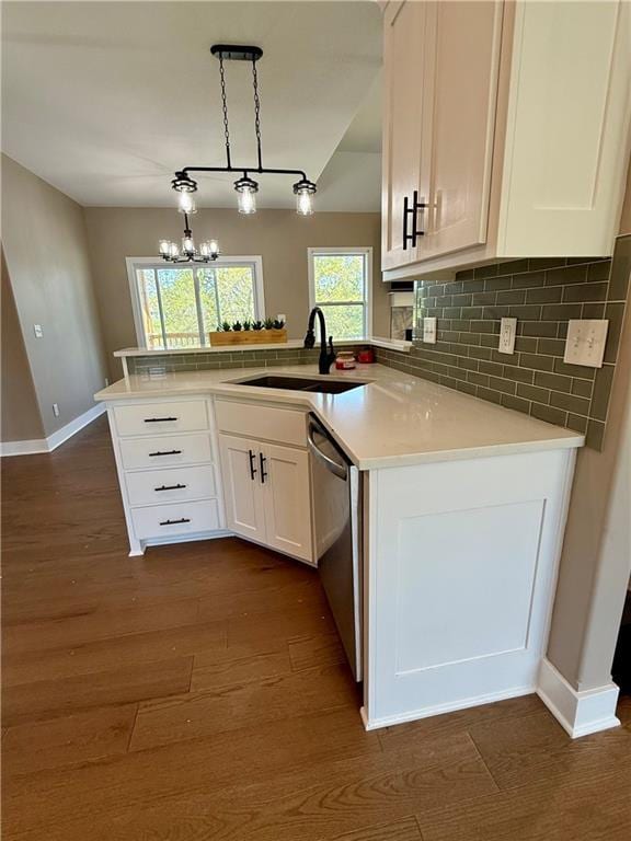 kitchen featuring a sink, decorative backsplash, dark wood-style floors, stainless steel dishwasher, and baseboards