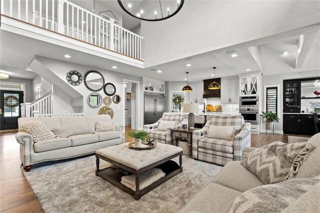 18050 N Peach Blossom Dr, Platte City, MO 64079 - living room featuring stairs, wood finished floors, a towering ceiling, recessed lighting, and a chandelier
