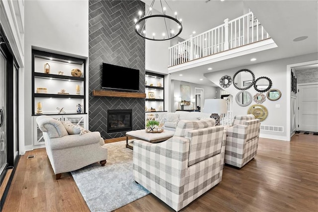 18050 N Peach Blossom Dr, Platte City, MO 64079 - living room featuring built in features, wood finished floors, baseboards, a towering ceiling, and a large fireplace