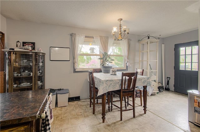 dining area with an inviting chandelier and a textured ceiling