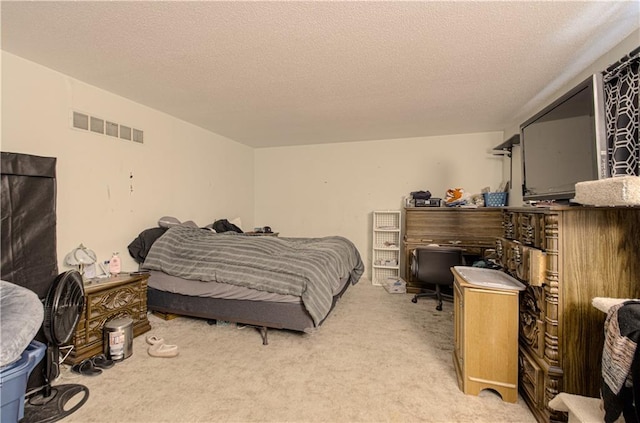 bedroom featuring light carpet, a textured ceiling, and visible vents