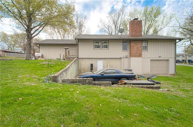 rear view of house with a garage, a lawn, and a chimney