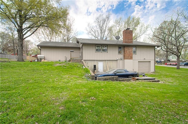 rear view of house featuring a chimney, a lawn, and a garage