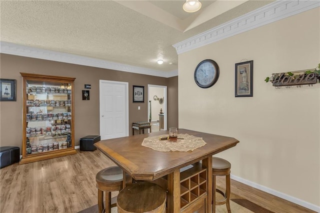 dining room featuring wood finished floors, baseboards, and a textured ceiling