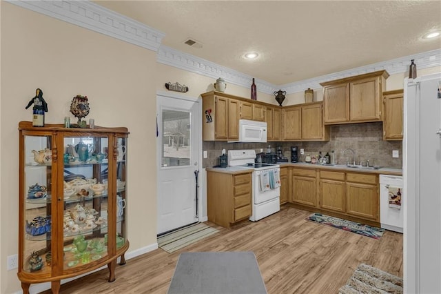 kitchen featuring white appliances, a sink, light wood-type flooring, decorative backsplash, and light countertops