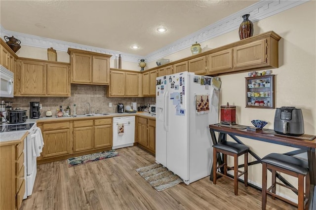 kitchen featuring white appliances, a sink, crown molding, light wood-type flooring, and light countertops