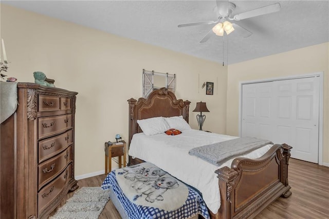 bedroom with wood finished floors, baseboards, a textured ceiling, and ceiling fan