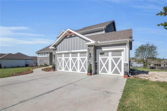 exterior space with a shingled roof, concrete driveway, an attached garage, board and batten siding, and stone siding
