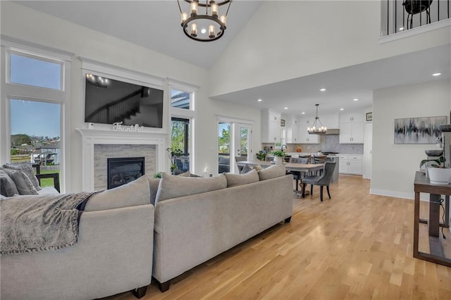 living room featuring recessed lighting, light wood-style floors, a notable chandelier, high vaulted ceiling, and a fireplace