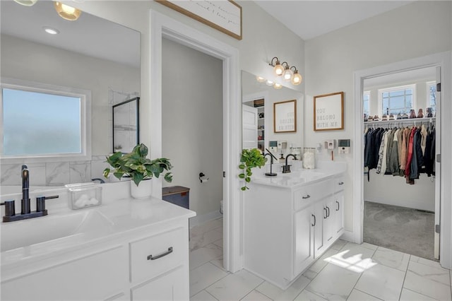 full bath featuring two vanities, marble finish floor, and a sink