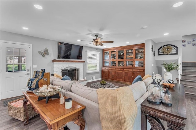 living area featuring wood finished floors, a fireplace, stairway, recessed lighting, and a ceiling fan