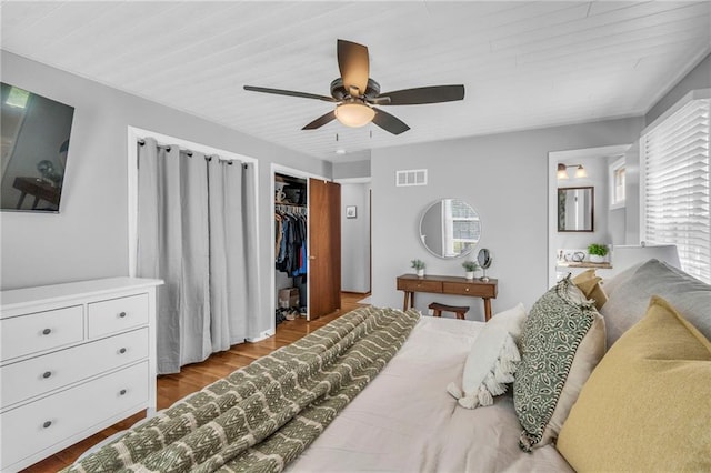 bedroom with ceiling fan, visible vents, wood finished floors, and a closet